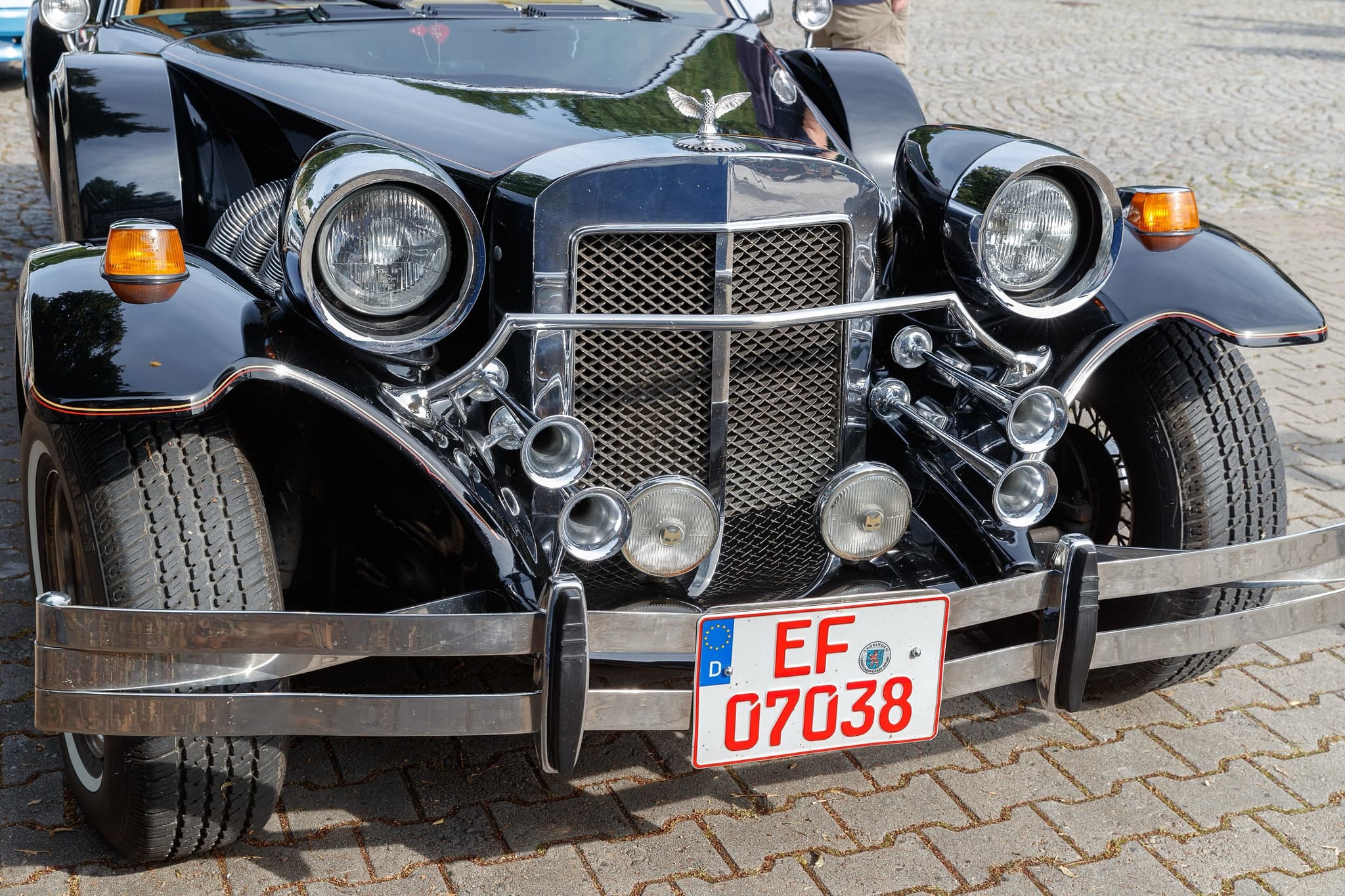 The front of a black Golden Spirit: two headlamps and two fog lamps, amber indicators, chrome trumpet horns and a mesh grille.