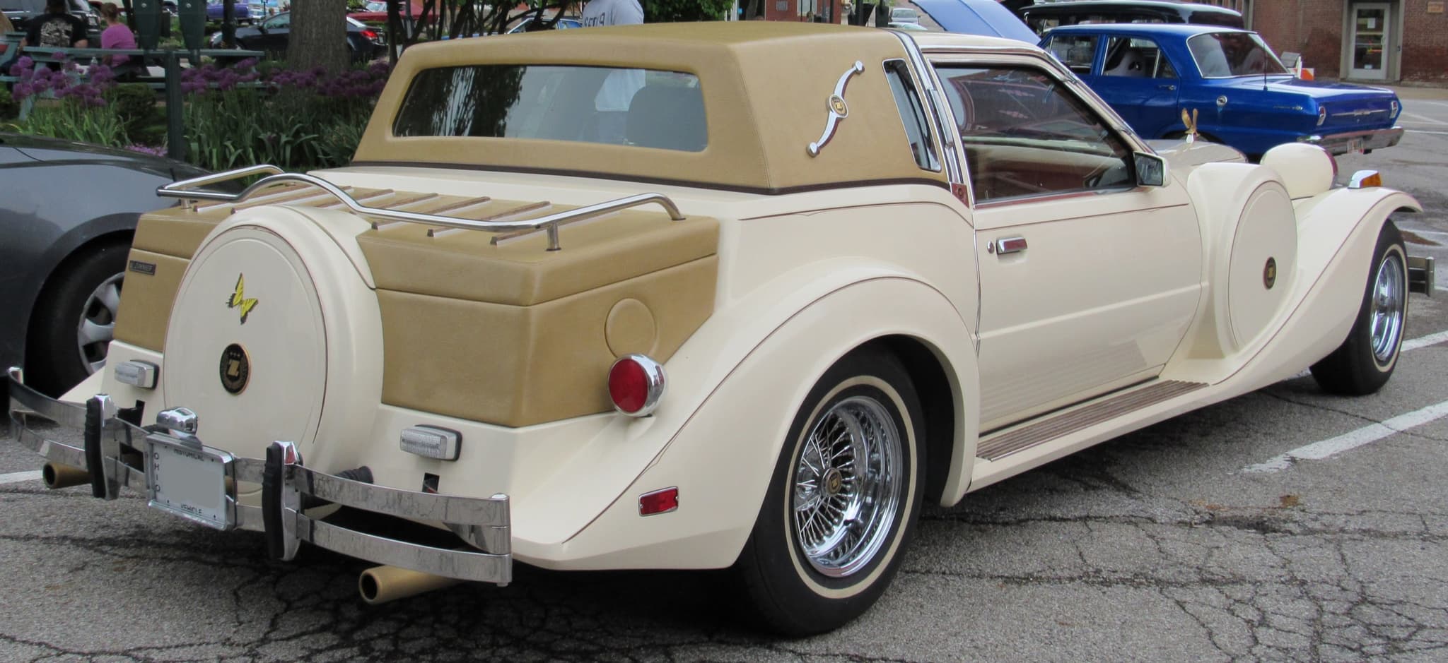 The rear of a cream Golden Spirit coupé with a luggage rack, a spare-wheel cover and a tan padded roof.